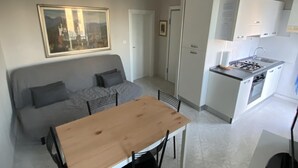 A compact living space with a kitchenette, a dining area, and a sofa. - Fairmont Residence Alice by Ca-sa Check (Chioggia)