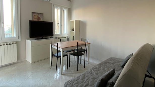 A modern living room with a sofa, a dining table with chairs, a TV, and a cabinet. - Fairmont Residence Alice by Ca-sa Check (Chioggia)