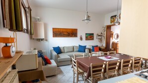 A living room with a sofa, dining table, and chairs. There is a radiator, a lamp, and a painting on the wall. - Casa Aprilia by Ca-sa Check (Venice)
