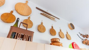 A kitchen with wooden utensils hanging on the wall, a bottle of olive oil, and a wooden chair. - Casa Aprilia by Ca-sa Check (Venice)