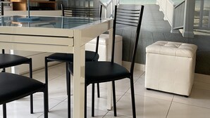 A dining area with a glass table, black chairs, a white cushioned bench, and a TV on a stand. - Fairmont Residence Elisabetta by Ca-sa Check (Chioggia)