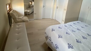 A bedroom with a bed, a chair, a mirror, and a door. - Fairmont Residence Elisabetta by Ca-sa Check (Chioggia)
