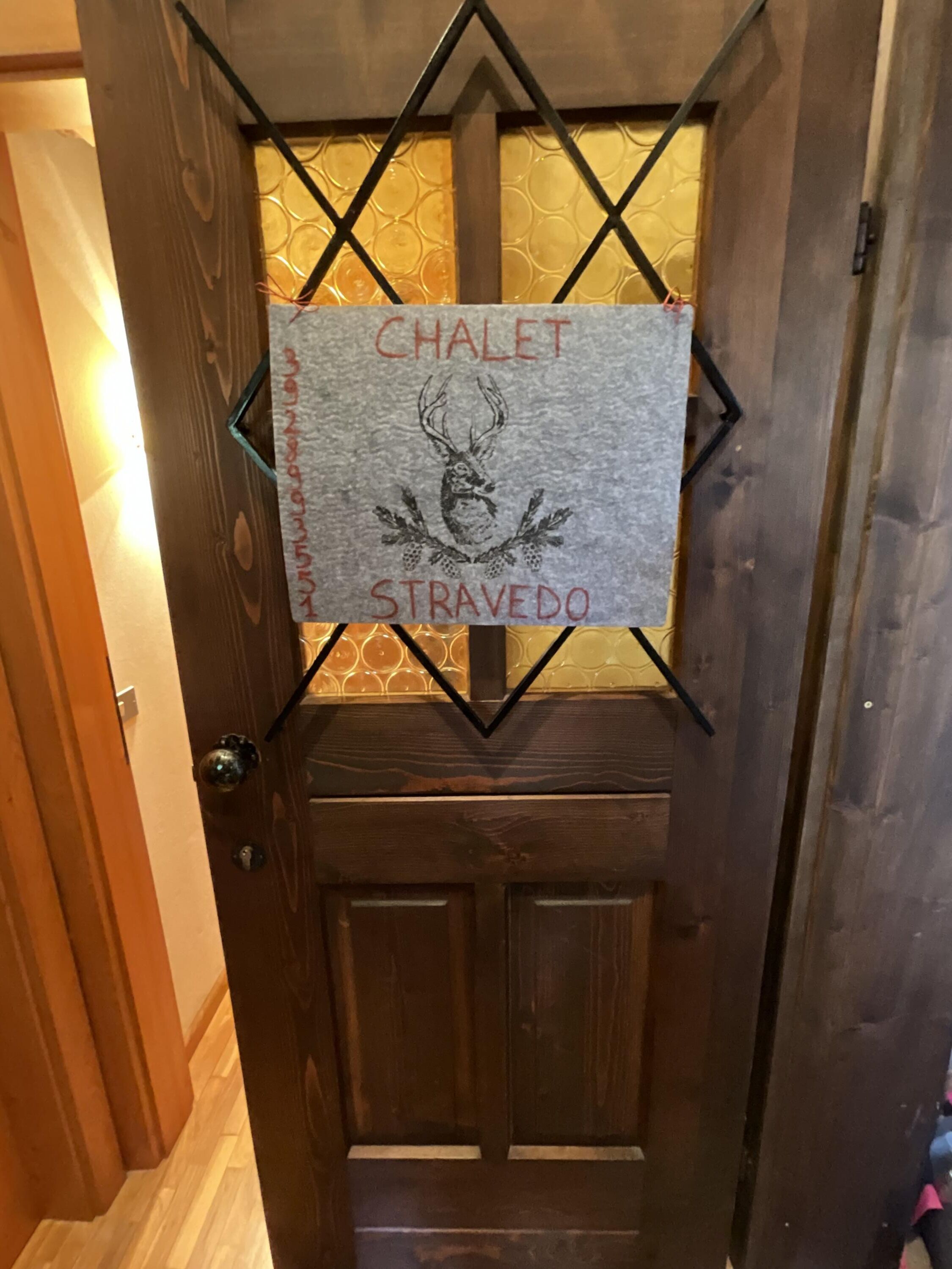 A door with a sign that reads "CHALET STRAVEDO" and a deer head logo.