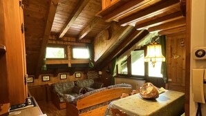 Een houten blokhut interieur met een eethoek, een raam met uitzicht en een plafondventilator.