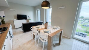 Une cuisine moderne avec un coin repas, un téléviseur à écran plat et une grande fenêtre donnant sur l’extérieur.