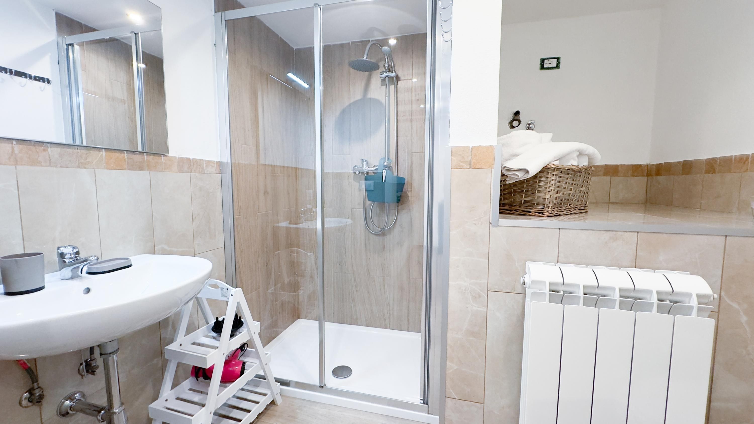 A modern bathroom with a glass-enclosed shower, a white sink, and a towel rack.