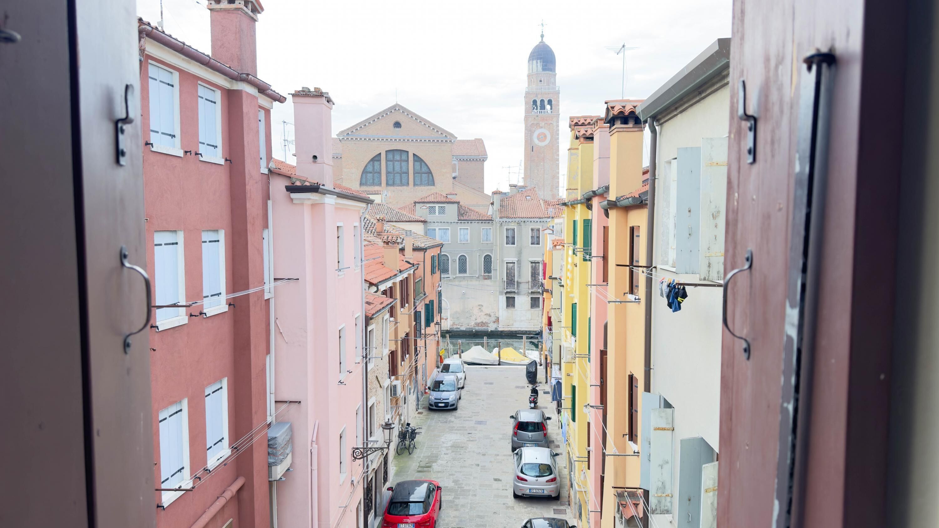 Una calle estrecha con edificios coloridos, una iglesia destacada y una torre.