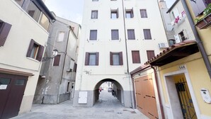 Un vialetto stretto con un arco centrale che conduce a un edificio con diverse finestre e un ingresso.