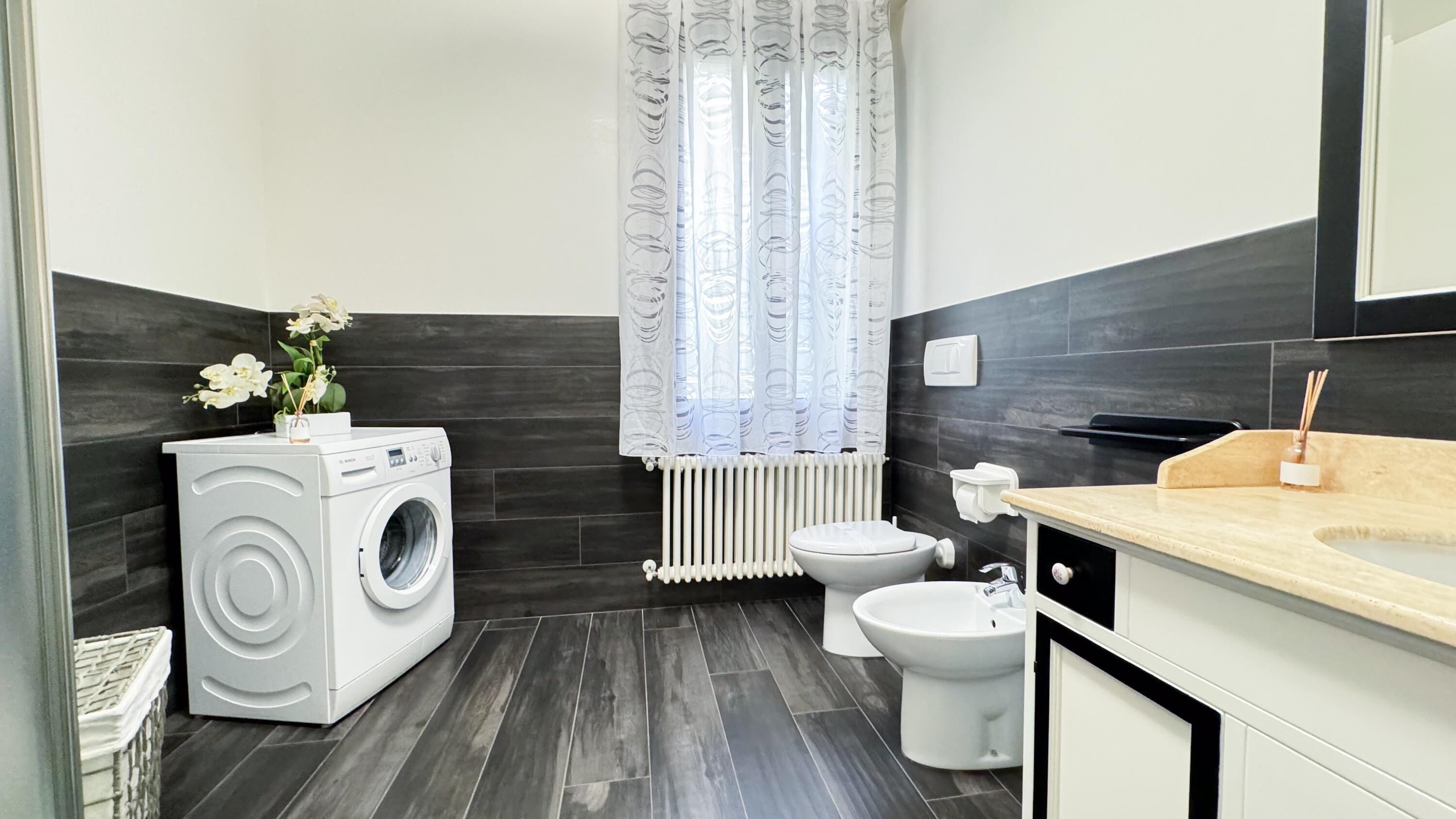 Et moderne badeværelse med en Bosch vaskemaskine, toilet og bidet.