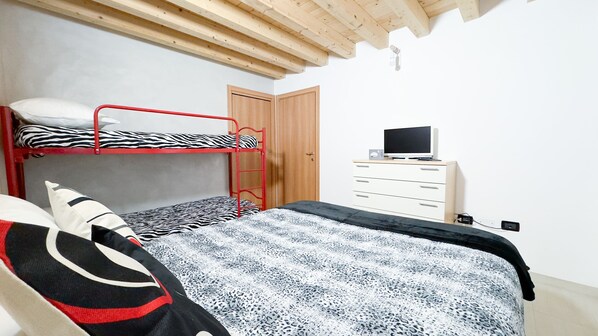 A bedroom with bunk beds, a dresser, a television, and a wooden ceiling. - Romantic Flower by Ca-sa Check (Chioggia)