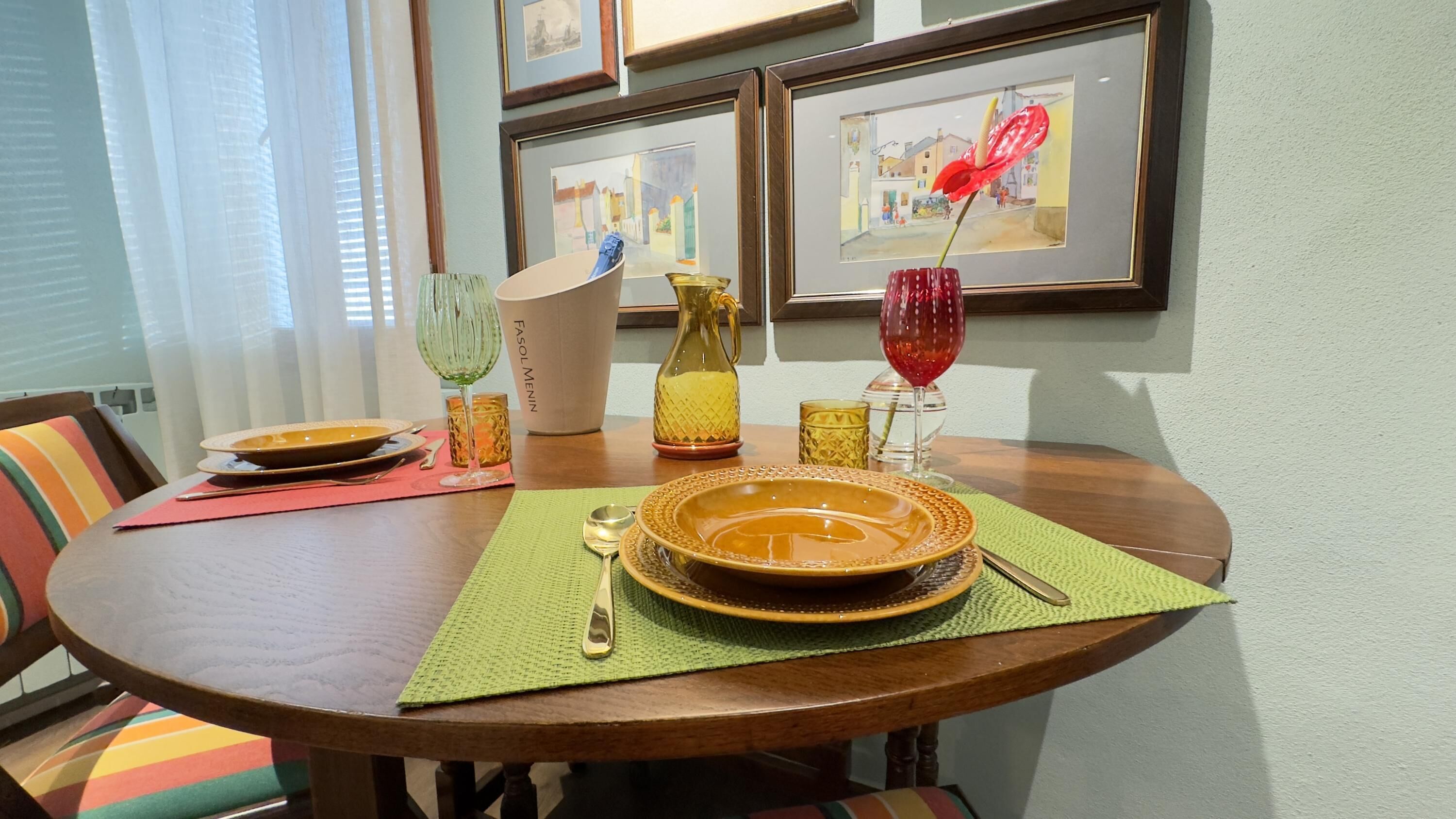 A dining table with a bowl, a pitcher, and a glass on a green placemat.