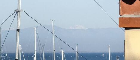 A coastal view with multiple tall structures, possibly communication towers, and a distant mountain range.