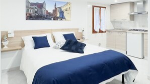 A modern hotel room with a large bed, a kitchen area, and a cityscape painting on the wall. - Blue Eyes by Ca-sa Check (Chioggia)