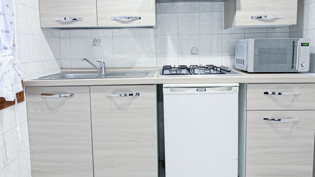 A modern kitchen with light wood cabinets, a stainless steel sink, a gas stove, and a microwave. - Blue Eyes by Ca-sa Check (Chioggia)