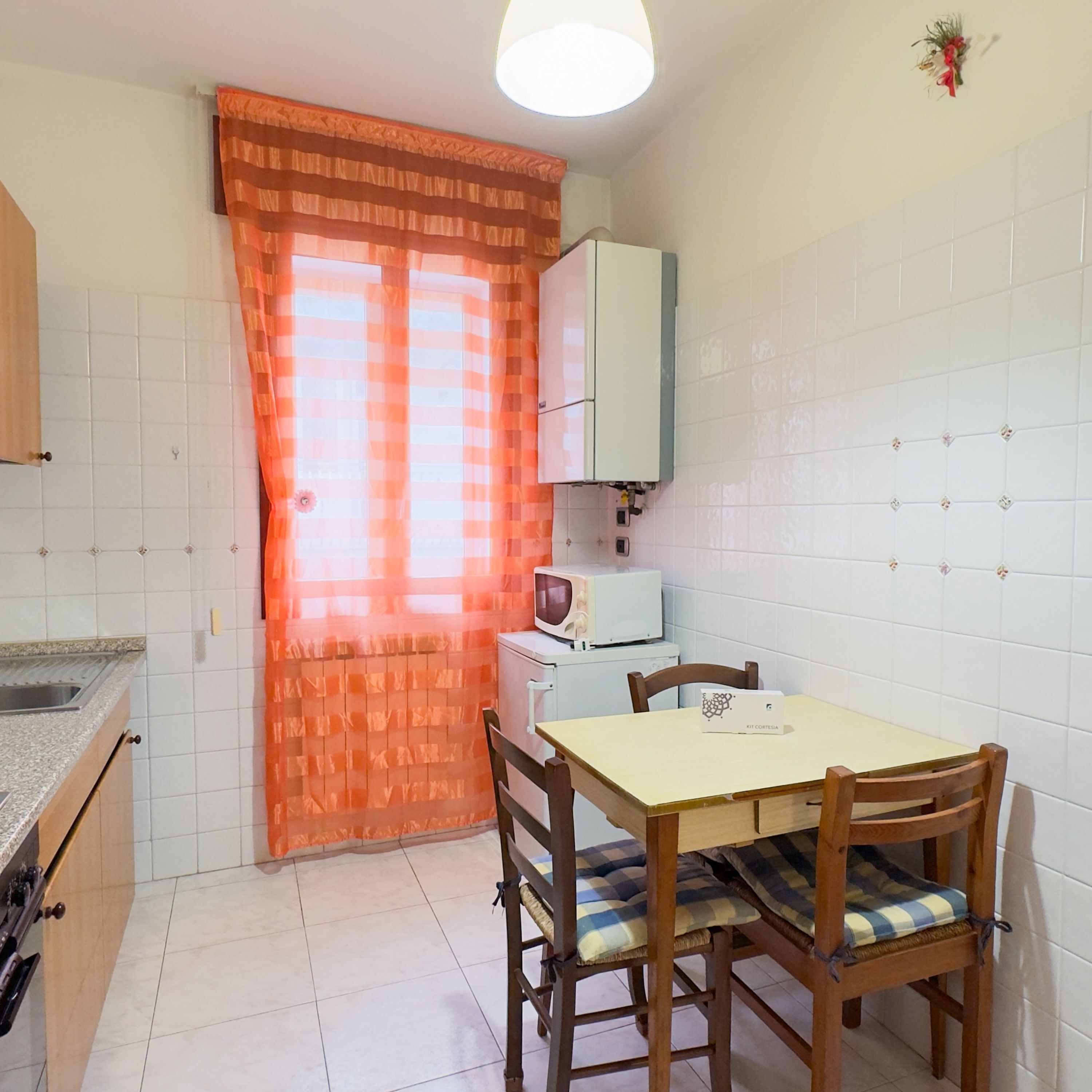 A small kitchen with a dining table, chairs, a microwave, and cabinets.