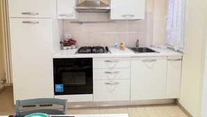 A compact kitchen with white cabinets, a stainless steel range hood, a built-in oven, and a sink. - Casa Dolce Casa by Ca-sa Check (Chioggia)