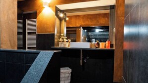A modern bathroom with a dark wood vanity, a white sink, and a mirror above it. There are toiletries on the counter and a towel rack to the left. - Da Nonna Liana - Centro storico di Lucca | Wifi (Lucca)