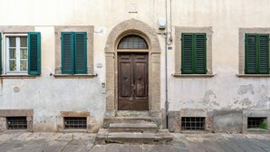 A building with a central arched doorway, flanked by windows with green shutters, and a stone-paved entrance. - Da Nonna Liana - Centro storico di Lucca | Wifi (Lucca)