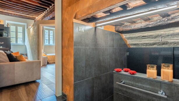A modern bathroom with dark tiles, a wooden ceiling, and a glass shower enclosure. - Da Nonna Liana - Centro storico di Lucca | Wifi (Lucca)