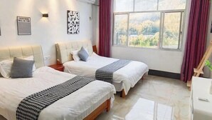 A hotel room with two beds, a large window with a view, a desk, and wall-mounted artwork. - Shennong Valley Xishui Hotel (Yanling)