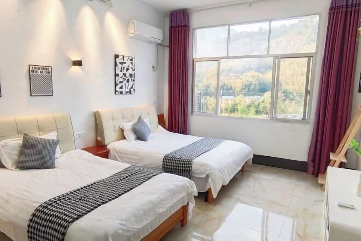 Ein Hotelzimmer mit zwei Betten, einem großen Fenster mit Blick, einem Schreibtisch und Wandbildern.
