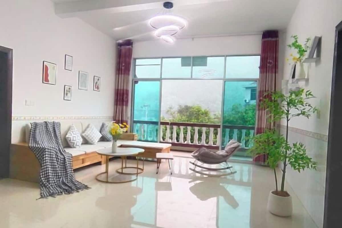 Ein modernes Wohnzimmer mit einer Couch, einem Couchtisch, einem Schaukelstuhl und einer Zimmerpflanze.