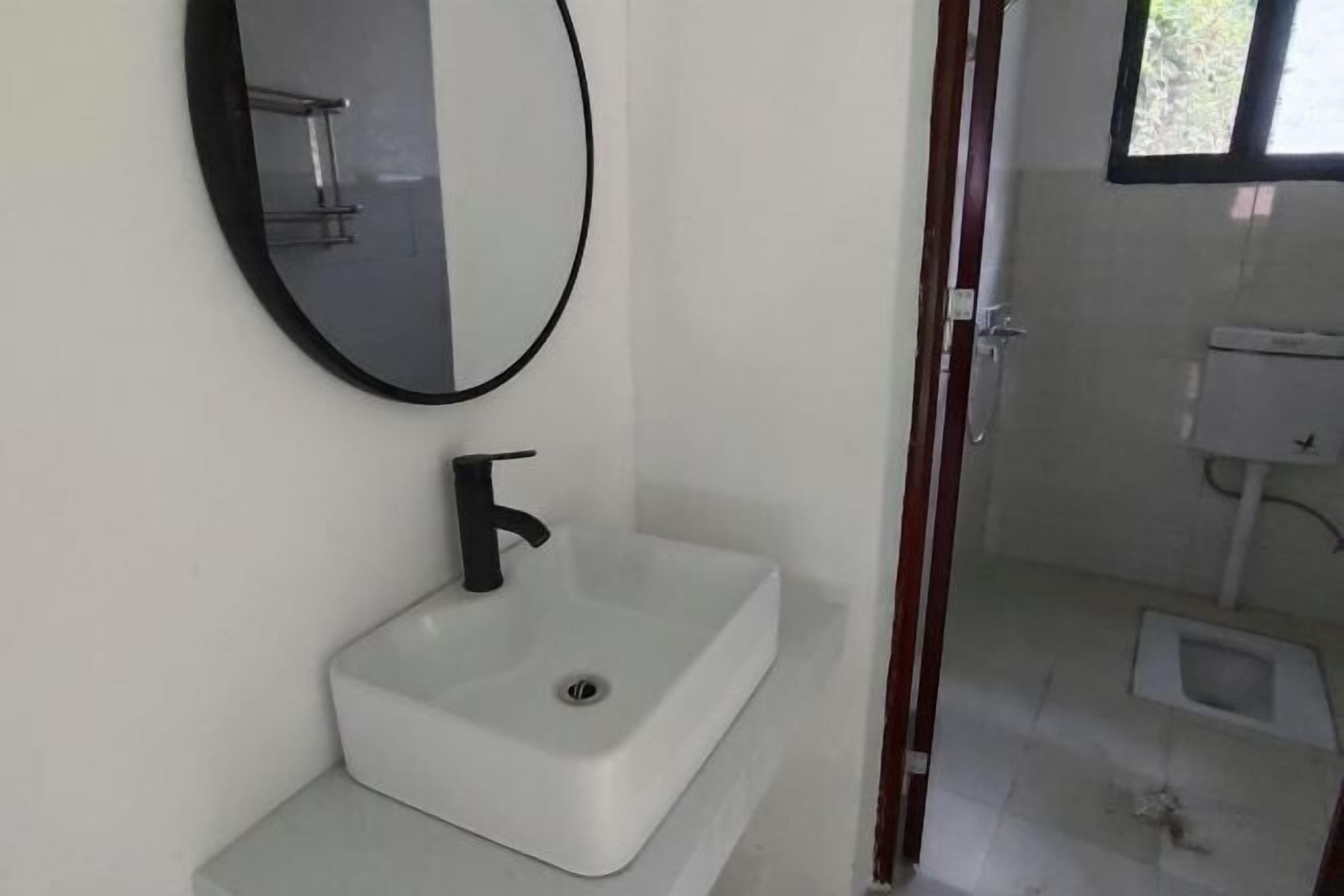 A bathroom with a white sink, black faucet, and a mirror.