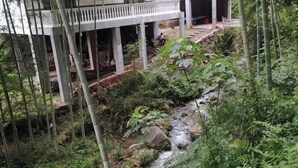 A building with a covered outdoor area, a stream, and surrounding greenery. - Shennong Valley Xishui Hotel (Yanling)