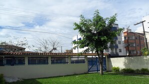 A residential area with a white building, a blue gate, and a tree in the foreground.