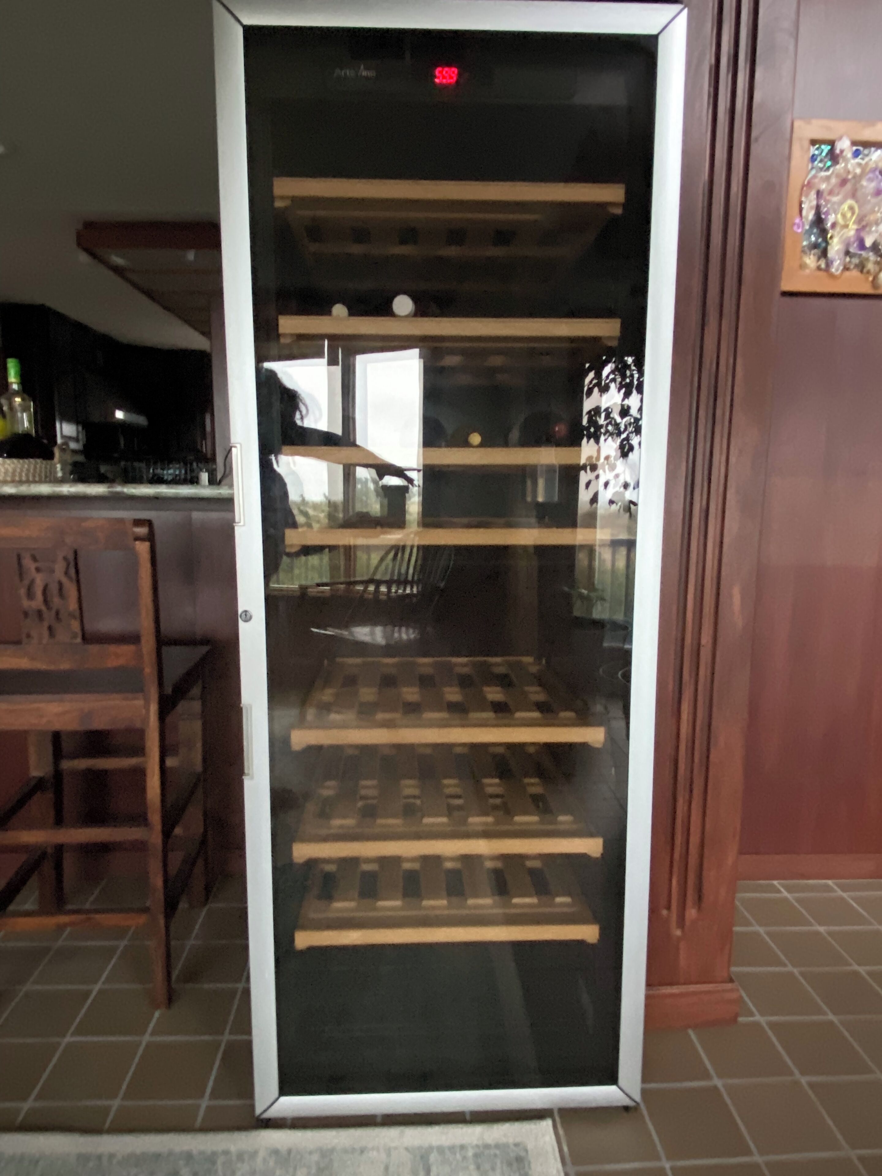 Quarto com porta de vidro, um banco de madeira no interior e uma cadeira no exterior.