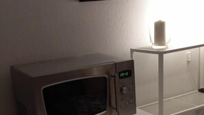 A microwave on a shelf, a framed text on the wall, and a candle on a table. - Charming studio in Avignon (Avignon)
