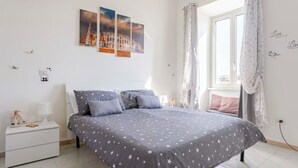 A bedroom with a bed, a nightstand, a window with curtains, and wall art. - Fefe's House (Roma)