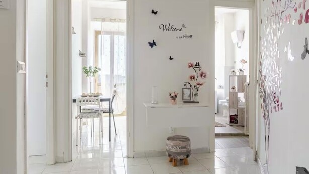 A bright hallway with a white wall, a welcome sign, and a small table with chairs. - Fefe's House (Roma)