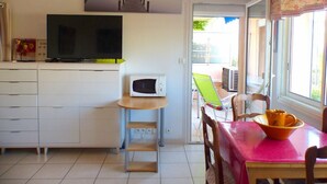 Une cuisine compacte équipée d’un four à micro-ondes, d’une télévision et d’un coin repas avec une table et des chaises.