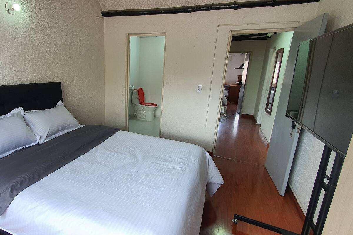 A bedroom with a bed, a wardrobe, and a bathroom visible through an open door.