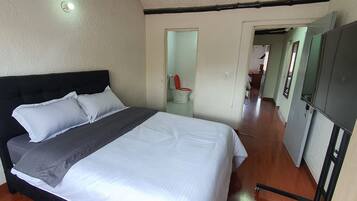Un dormitorio con cama, armario y baño a la vista a través de una puerta abierta.