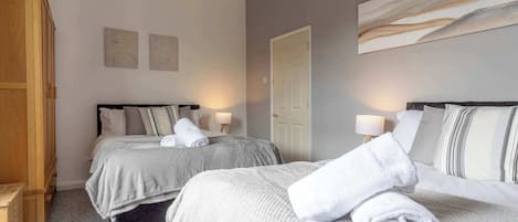 A hotel room with two beds, a wooden wardrobe, and a door.