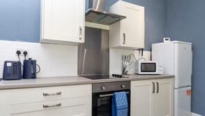 A kitchen with white cabinets, a stainless steel range hood, a microwave, and a built-in oven. - Large 4 Bedroom House Sleeps 9 With WiFi (Stockton-on-Tees)