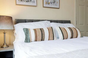 A neatly made bed with white linens and striped pillows, a bedside lamp, and two motivational posters on the wall. - Comfortable 3 Bedroom Home Sleeps 5 (Stockton-on-Tees)