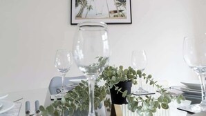 A dining table set with clear glassware, a potted plant, and a framed picture on the wall. - Comfortable 3 Bedroom Home Sleeps 5 (Stockton-on-Tees)