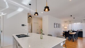 A modern kitchen with a large island, pendant lighting, and a dining area with a table and chairs.
