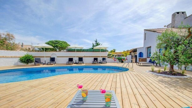 Ein Poolbereich mit Holzterrasse, Liegestühlen und einem Tisch mit Getränken.