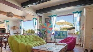 Ein geräumiges Wohnzimmer mit einem grünen Sofa, einem pinken Sitzsack und einem Holztisch.