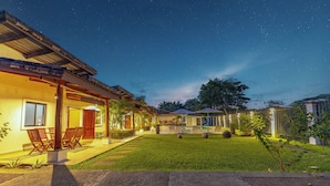 Un espacio exterior bien iluminado con patio, mobiliario y una piscina.
