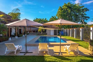 Relax by the serene pool surrounded by lush greenery and a patio.