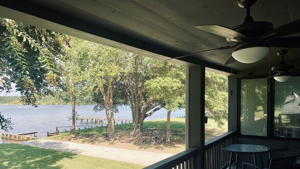 A covered outdoor area with a view of a lake, a wooden dock, and a grassy lawn. - Family friendly lakefront home with private boat ramp and dock (Summerton)