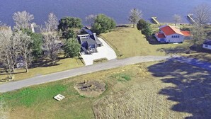 A lakeside property with a large house, a dock, and a boat. - Family friendly lakefront home with private boat ramp and dock (Summerton)