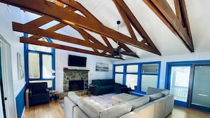 A spacious living room with a large sectional sofa, a stone fireplace, and a ceiling fan. - Family friendly lakefront home with private boat ramp and dock (Summerton)