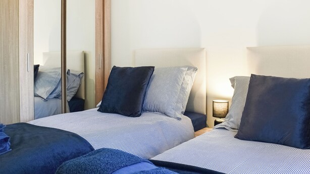 Een slaapkamer met twee bedden, een kledingkast en een bedlampje.