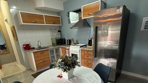 Een moderne keuken met een eettafel, stoelen en een koelkast.